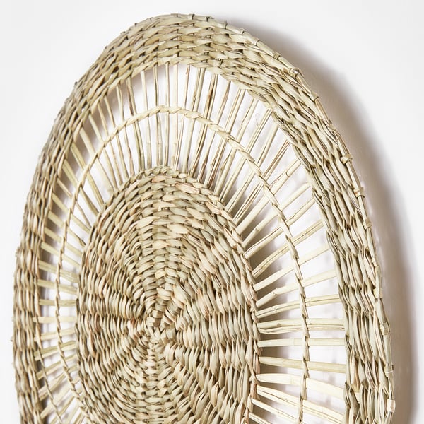 Handwoven sedge wall art, circular. Intricate natural design, high craftsmanship.