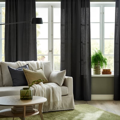 Modern living room with dark grey curtains, cosy sofa, and minimalist decor.