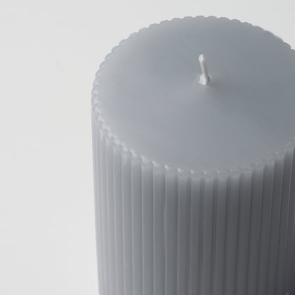 Close-up of elegant gray pillar candle with vertical grooves, unlit wick, smooth texture.