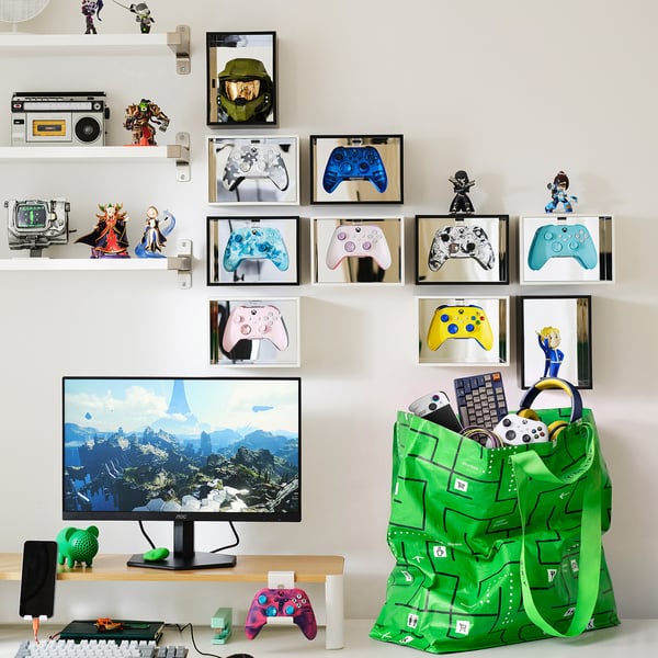 Green GÖTEHULT bag with gaming gear, controllers, figures, and gold helmet above monitor.