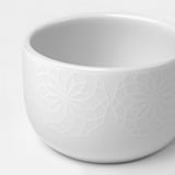 Elegant white porcelain cup with embossed geometric design. Smooth, durable surface.