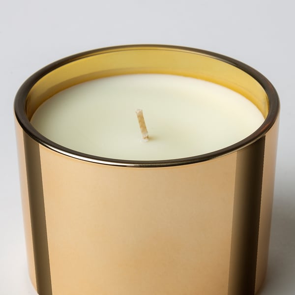 Large scented candle in elegant gold jar, ready to be lit for warm ambiance.