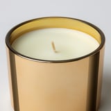 Large scented candle in elegant gold jar, ready to be lit for warm ambiance.