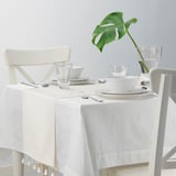 White table set with dishes and runner with tassels.