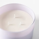 Round lavender glass candle jar with three unlit white wicks.