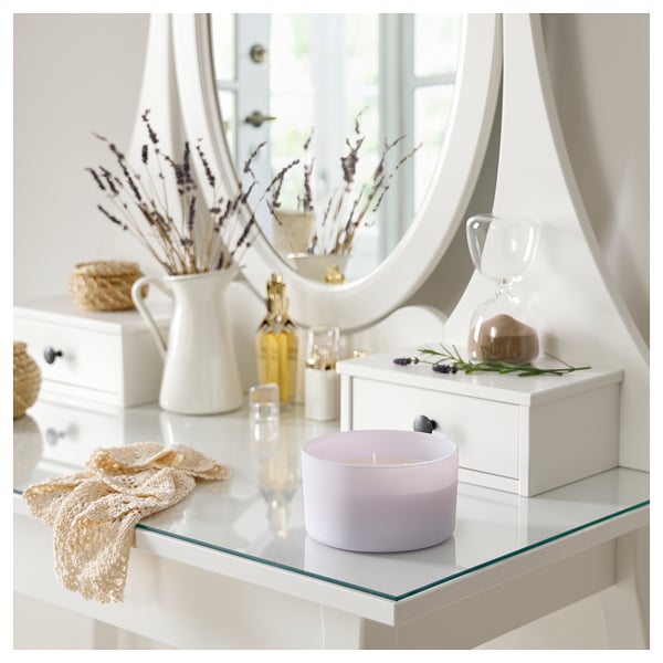 White vanity with lavender candle, mirror, vase, and decor.