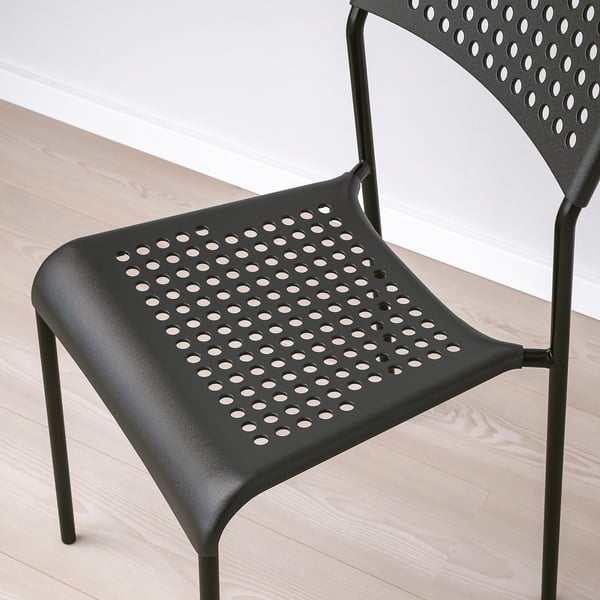 Black plastic chair with circular seat and back patterns on a wooden floor.