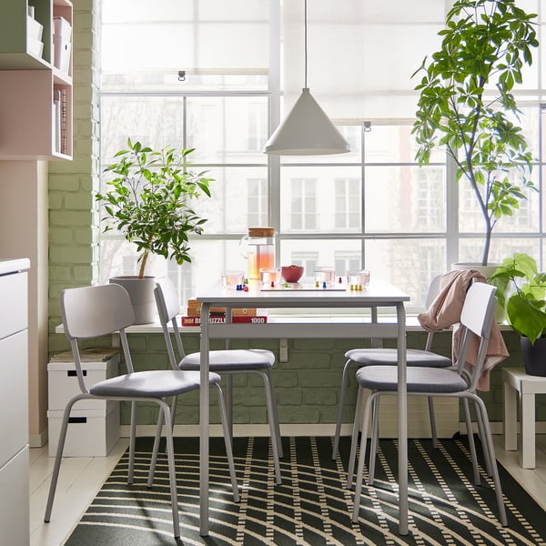 Modern dining set with four grey GRÅSALA chairs around a square table. Large windows and plants decorate the bright room.