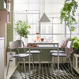 Modern dining set with four grey GRÅSALA chairs around a square table. Large windows and plants decorate the bright room.