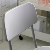 Light gray modern chair, sleek design with curved back, upholstered seat.