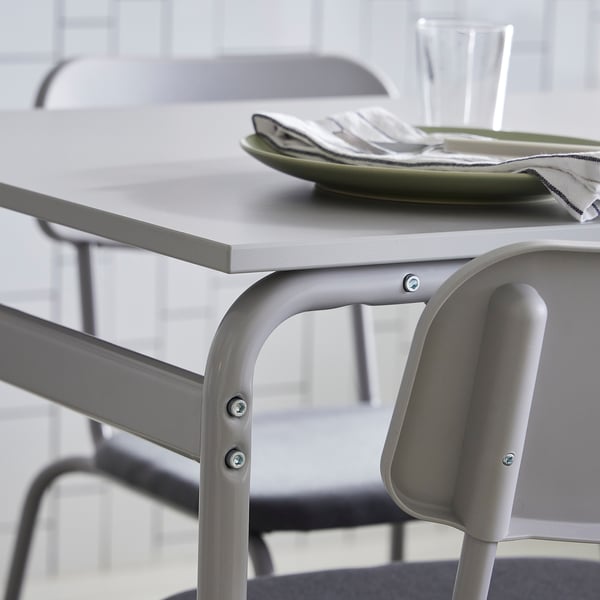 Modern grey metal table with minimalist design, holding a green plate and folded napkin. Perfect for compact dining spaces.