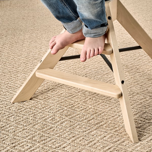 Child climbing wooden junior chair with footrest, designed for dining table height.