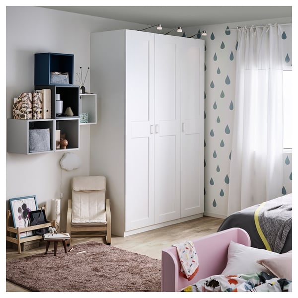 Modern bedroom with white GRIMO wardrobe, pink bed, colorful pillows, wooden chair, rug, and wall shelves.
