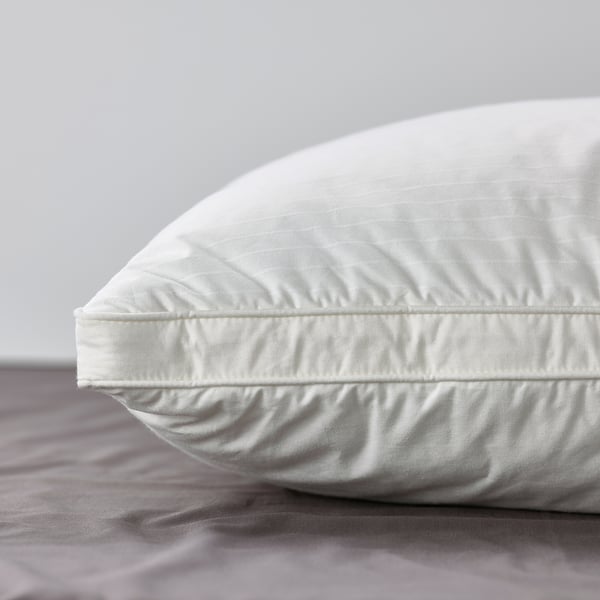 Close-up of a plush, white pillow on grey sheets, showcasing soft cotton and comfy design.