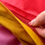 A hand zips a colorful baby duvet, showing its safety feature.