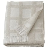 A beige GRÖNKNAVEL throw blanket with fringe detail around the edges, made from 100% recycled polyester.