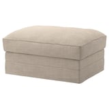 Depicts a beige-colored, rectangular-shaped footstool with a padded, textured fabric cover. It has a simple, modern design with smooth, rounded edges.