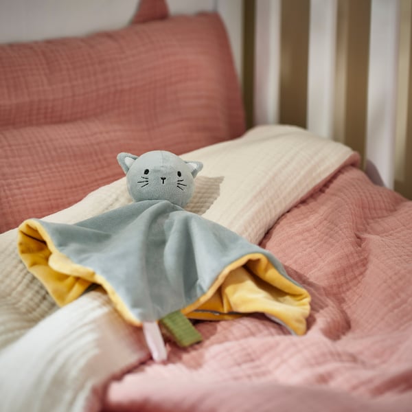 Soft grey cat toy on pale pink blanket; cozy, recycled material.