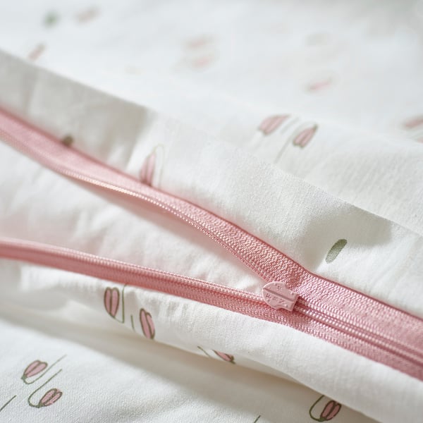Close-up of a white duvet cover with pink flowers and zipper, made of organic cotton.