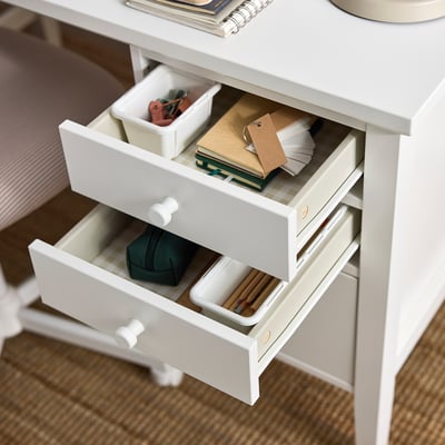 White desk with three open drawers showing organised stationery items.