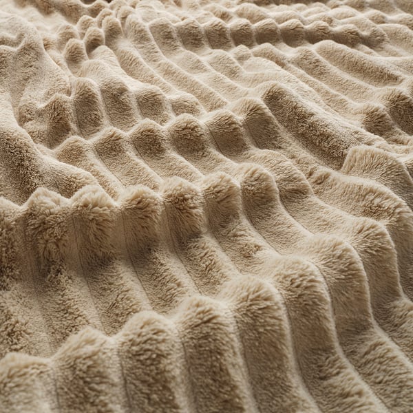 Soft beige woven blanket with frayed edges, showcasing a cozy, textured pattern.