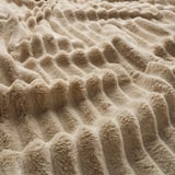 Soft beige woven blanket with frayed edges, showcasing a cozy, textured pattern.