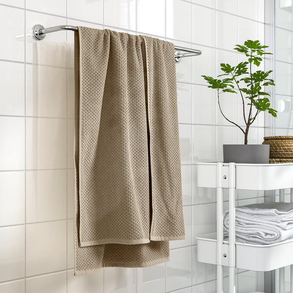 Modern bathroom with GULVIAL towel from ikea on rail, soft 100% cotton. White tiles, shelving with towels & plant, clean decor.