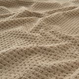 Beige cotton towel close-up, showcasing soft, fluffy texture and intricate weave.