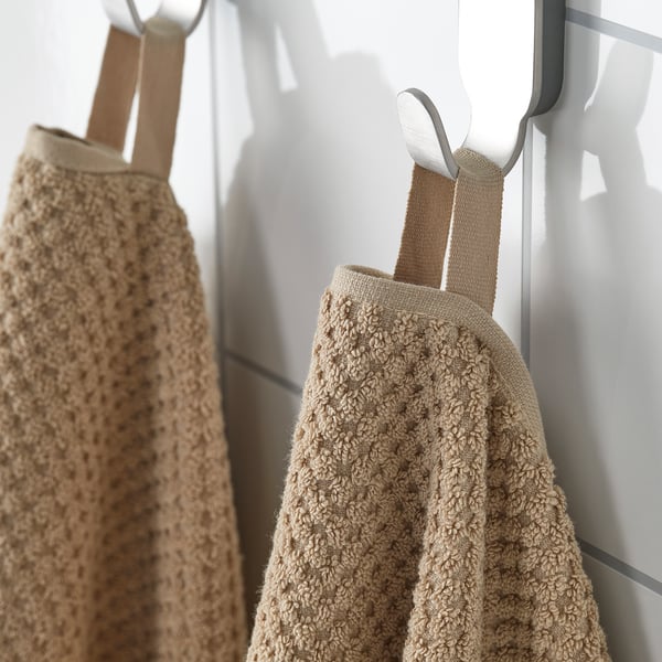 Beige towels hang neatly; soft, absorbent, cotton; ideal for everyday use.