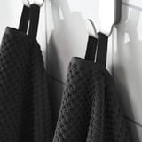 Two plush GULVIAL towels hang neatly, showcasing their soft, fluffy texture and white hooks.
