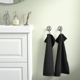 Two towels hang on hooks beside a white sink cabinet.