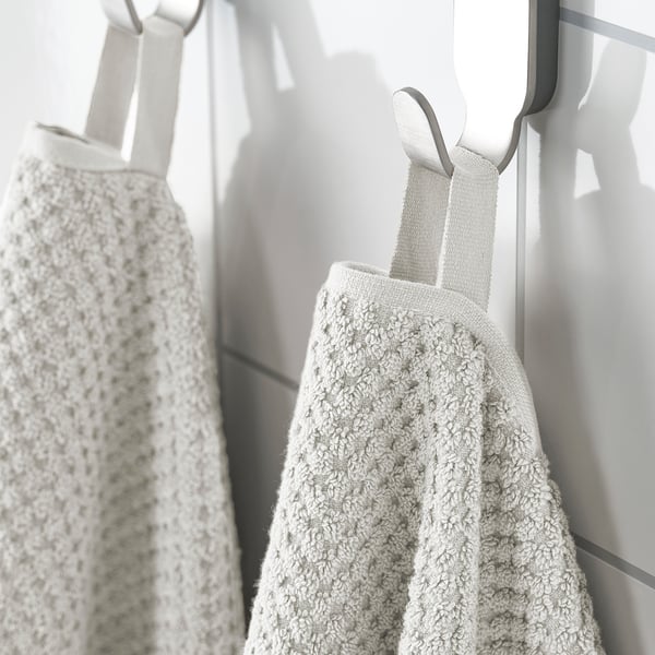 Two beige towels hang side by side, soft, absorbent, and durable, ideal for daily use.