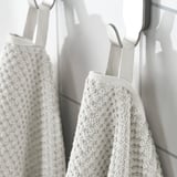 Two beige towels hang side by side, soft, absorbent, and durable, ideal for daily use.