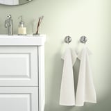 A bathroom with a white vanity, soft beige GULVIAL towels, and chrome hooks. Light color scheme.