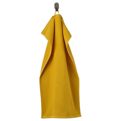 A bright yellow towel named GULVIAL hanging on a hook, made of 100% cotton.