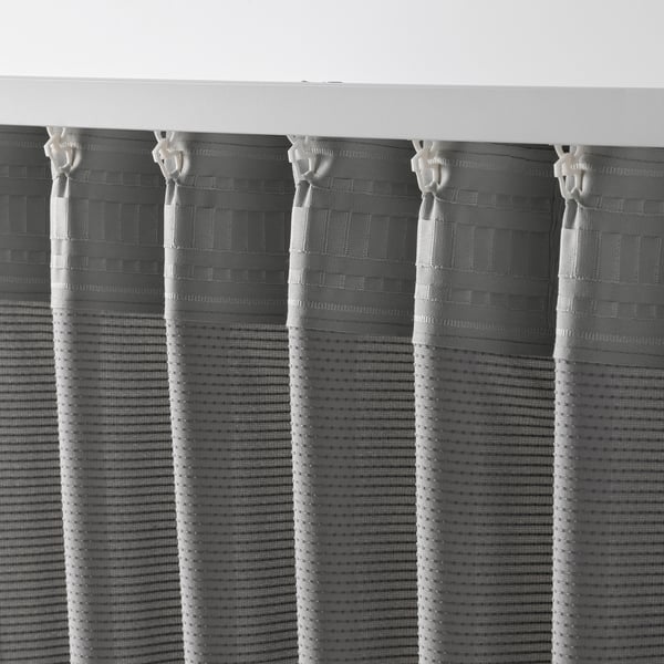Five hanging sound-absorbing curtains with vertical white hooks, filtering light, creating folds for sound dampening.