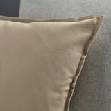 A close-up of a beige GURLI cushion with a smooth texture and hidden zipper, made of high-quality cotton.