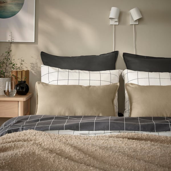 Bed with GURLI black & beige grid pillows and neutral bedding; pillows larger than small vase.