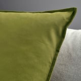 Close-up of a green cushion cover, smooth texture, zipper detail, set against plain background.