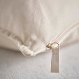 Close-up of high-quality beige cotton cushion cover with a drawstring zipper and loop.