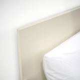 Bed frame corner with clean, cream finish against white wall.