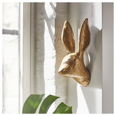 Gold rabbit-shaped wall decor with long ears, mounted on a light-colored wall, adding a playful touch to home decor.