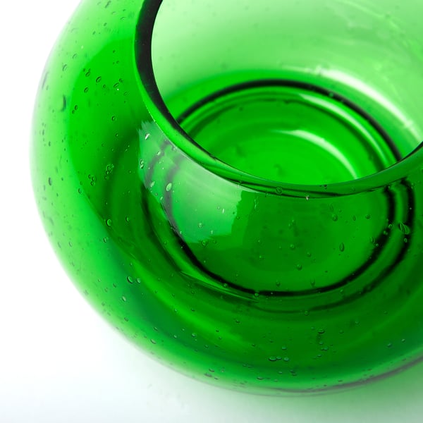 Close-up of vibrant green recycled glass candle holder, showcasing its bubbled texture and smooth finish.