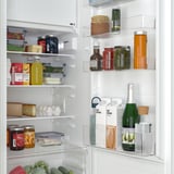Well-organized fridge with adjustable shelves, holding fruits, vegetables, cheeses, drinks, and condiments in a neat arrangement.