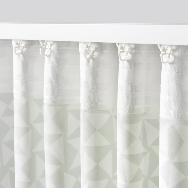White curtains with green triangular patterns hanging, blocking view while allowing light through, with hooks for easy adjustment.