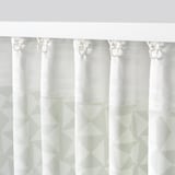 White curtains with green triangular patterns hanging, blocking view while allowing light through, with hooks for easy adjustment.