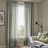 Green-white triangle curtains hang by window, recycled polyester, slightly longer than sofa and chair, creating fresh, private atmosphere.