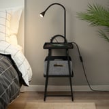 Black bedside table with built-in light and shelves. Ideal for small spaces, positioned beside a bed with geometric pillows.