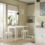 Modern kitchen with white HAUGA drop-leaf table and stools, greenery, and minimalist decor.