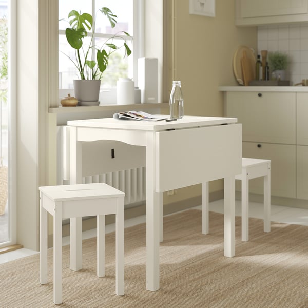 Small white kitchen setup, featuring HAUGA drop-leaf table and stools in bright, natural wood finish.